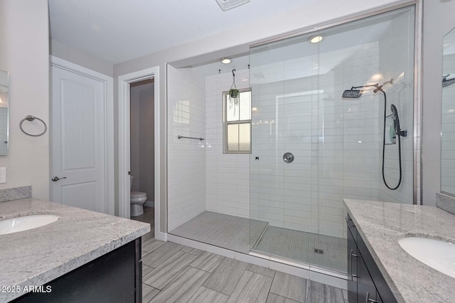 bathroom featuring vanity, toilet, and a tile shower