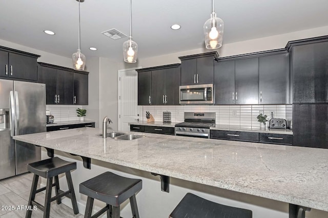 kitchen with decorative light fixtures, sink, stainless steel appliances, and a breakfast bar