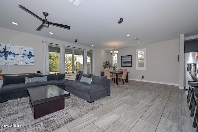 living room featuring ceiling fan with notable chandelier