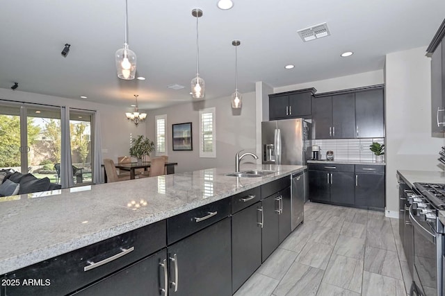 kitchen featuring appliances with stainless steel finishes, tasteful backsplash, sink, decorative light fixtures, and light stone counters