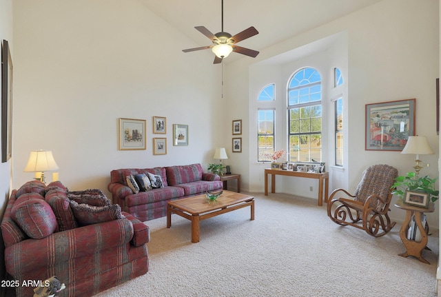 living room with carpet flooring, ceiling fan, and a towering ceiling