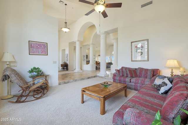 living room featuring decorative columns, ceiling fan, a towering ceiling, and carpet floors