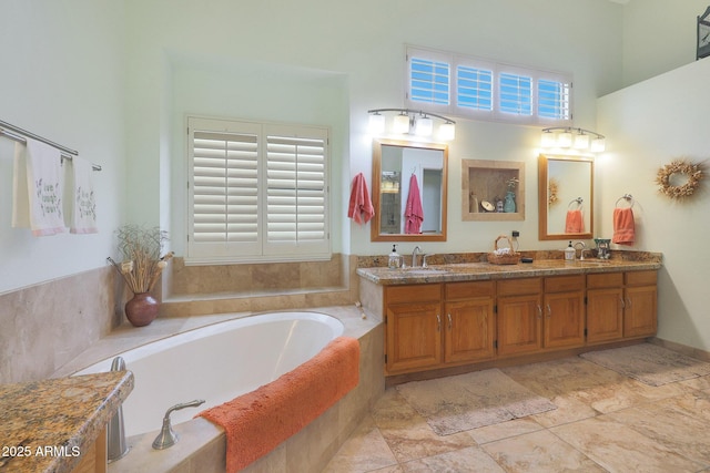 bathroom with vanity, tiled bath, and plenty of natural light