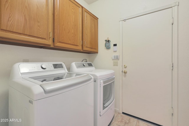 laundry area featuring washer and dryer, light tile patterned floors, and cabinets