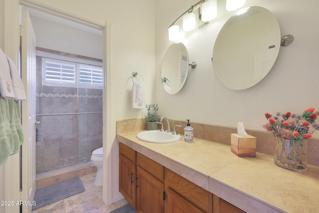 bathroom featuring tile patterned floors, vanity, tiled shower, and toilet