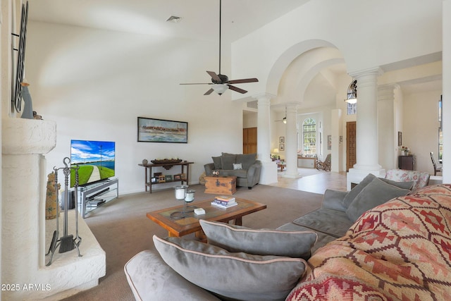 carpeted living room featuring ornate columns, ceiling fan, and high vaulted ceiling