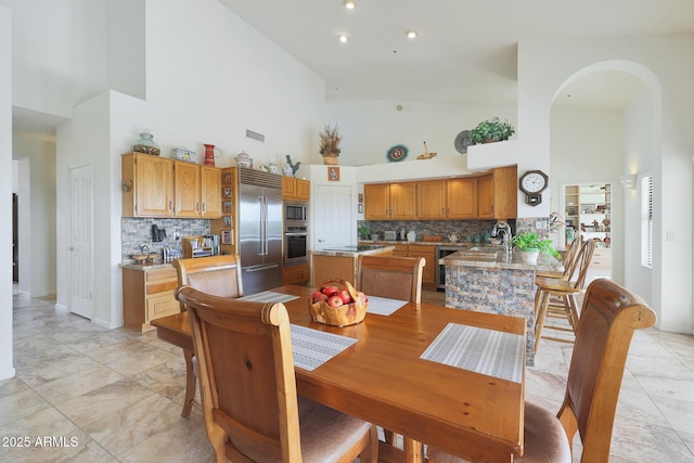 dining space featuring wine cooler, sink, and high vaulted ceiling