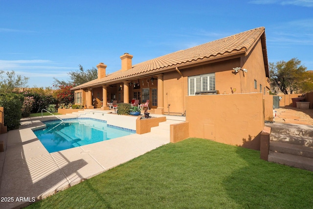 rear view of property with a yard, a fenced in pool, ceiling fan, and a patio area