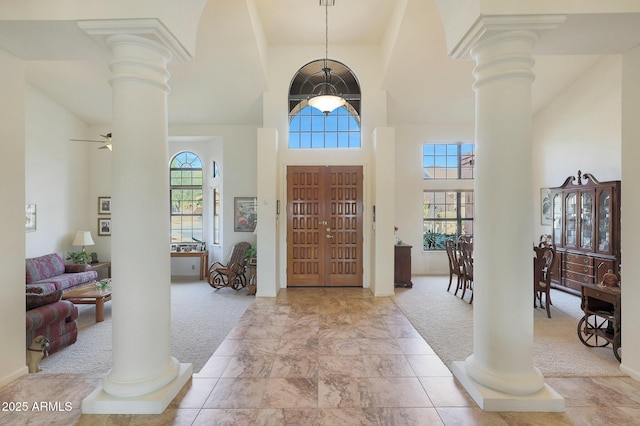 entrance foyer with ceiling fan, a towering ceiling, and light carpet