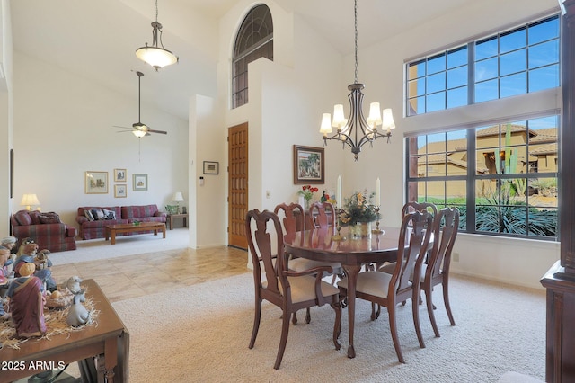 dining room with light carpet, a towering ceiling, and ceiling fan with notable chandelier