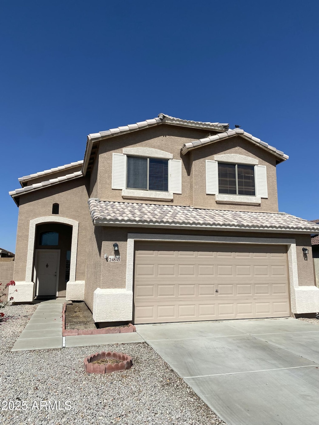 traditional-style home featuring stucco siding, concrete driveway, an attached garage, and a tiled roof