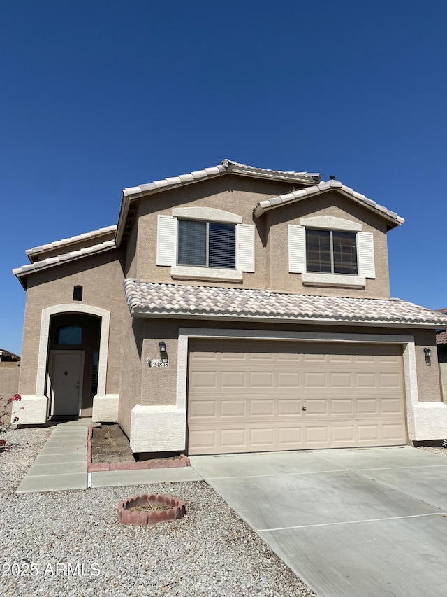 traditional-style house featuring a tiled roof, a garage, driveway, and stucco siding