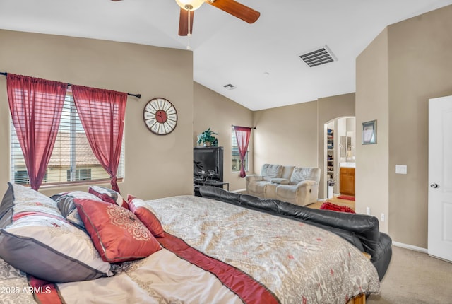 bedroom with lofted ceiling, visible vents, arched walkways, and carpet floors