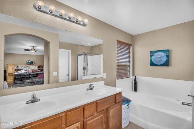ensuite bathroom featuring a sink, connected bathroom, a garden tub, and a ceiling fan