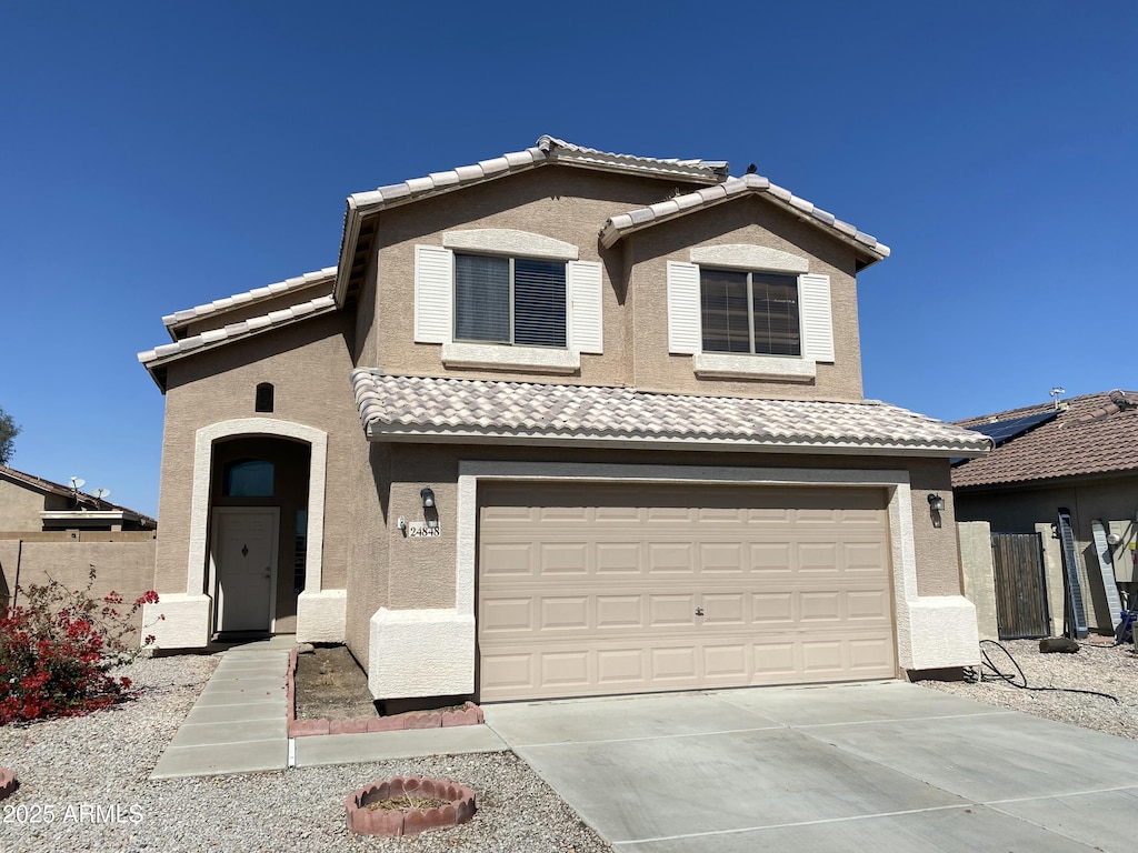 traditional home with a tiled roof, stucco siding, and an attached garage