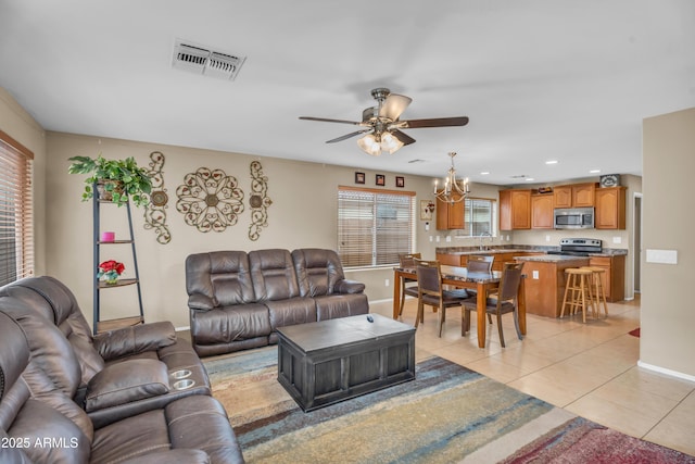 living room with visible vents, ceiling fan with notable chandelier, recessed lighting, light tile patterned floors, and baseboards