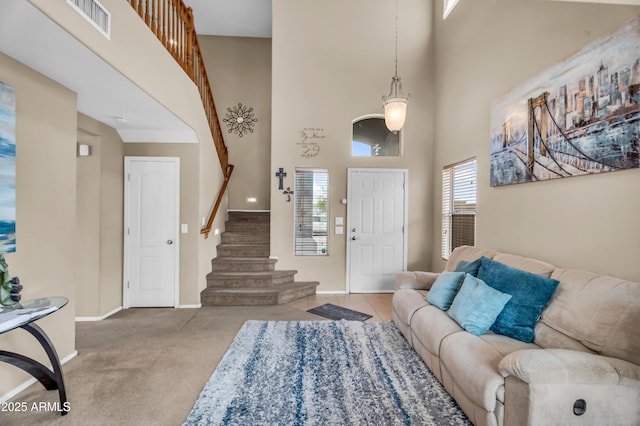 carpeted entryway featuring stairway, visible vents, baseboards, and a towering ceiling