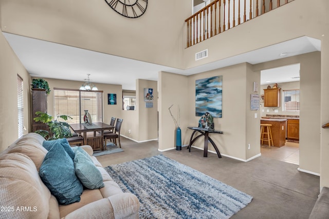 living area with baseboards, visible vents, light carpet, and an inviting chandelier