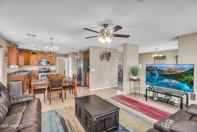 living room featuring light tile patterned floors, ceiling fan with notable chandelier, visible vents, and baseboards