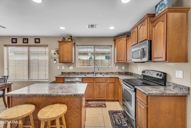 kitchen with a breakfast bar area, light tile patterned floors, visible vents, a sink, and stainless steel appliances