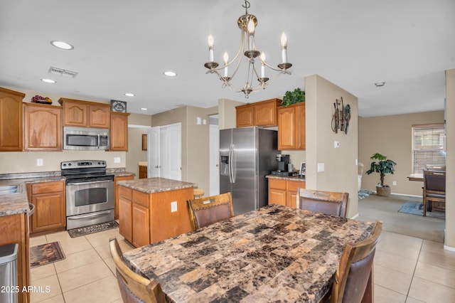 kitchen featuring visible vents, a center island, light tile patterned floors, appliances with stainless steel finishes, and an inviting chandelier