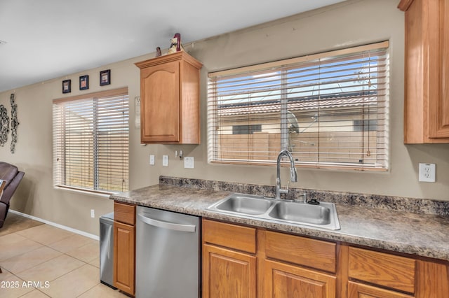 kitchen featuring baseboards, dishwasher, brown cabinets, light tile patterned flooring, and a sink