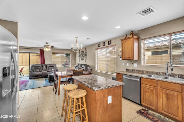 kitchen with light tile patterned floors, visible vents, a sink, stainless steel appliances, and a center island