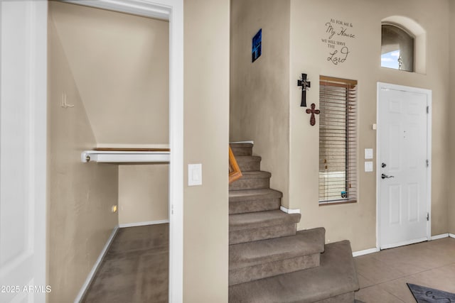 entryway featuring tile patterned floors, baseboards, and stairs