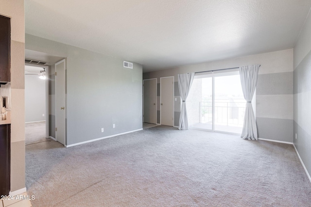 carpeted spare room featuring ceiling fan and a textured ceiling