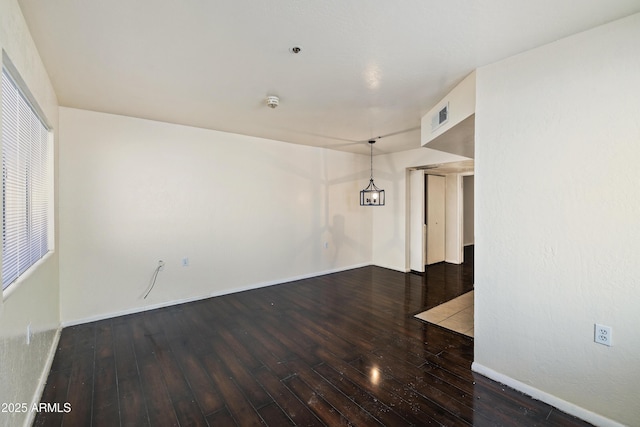 unfurnished room with visible vents, baseboards, and hardwood / wood-style floors