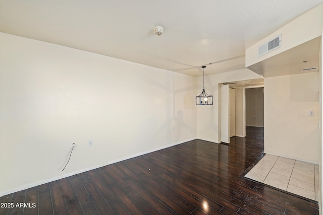 spare room featuring hardwood / wood-style flooring, baseboards, and visible vents