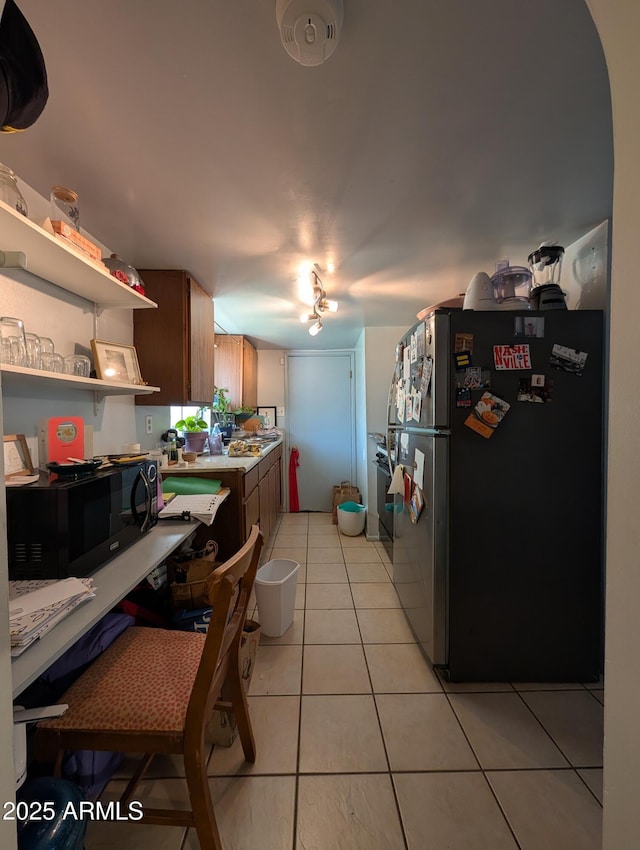 3827 N 8th St, Phoenix, AZ 85014 - kitchen with freestanding refrigerator, black microwave, light tile patterned floors, and open shelves