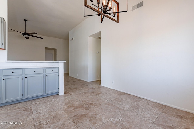 unfurnished living room featuring ceiling fan with notable chandelier and vaulted ceiling