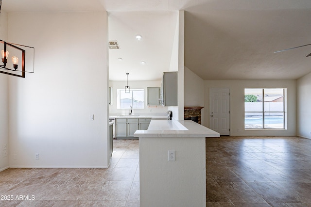 kitchen featuring gray cabinetry, plenty of natural light, kitchen peninsula, and sink