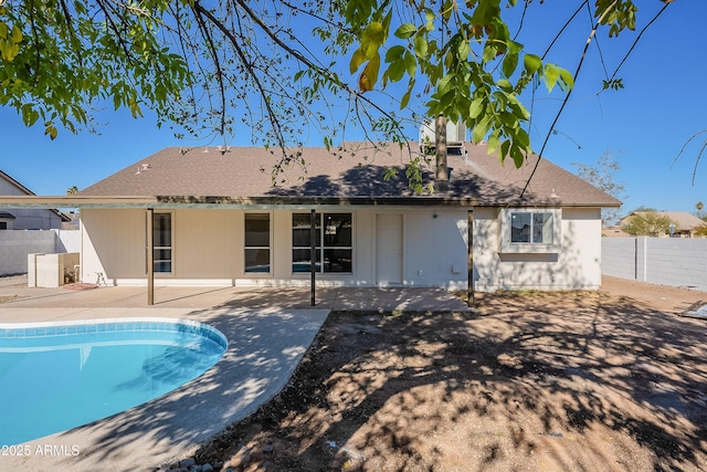 rear view of property with a fenced in pool and a patio