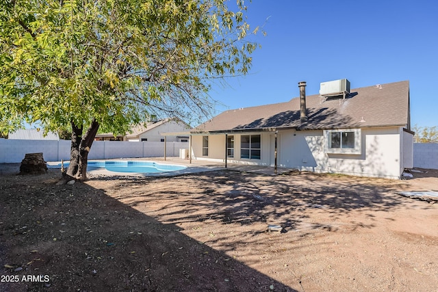 rear view of house featuring a fenced in pool, central AC, and a patio area