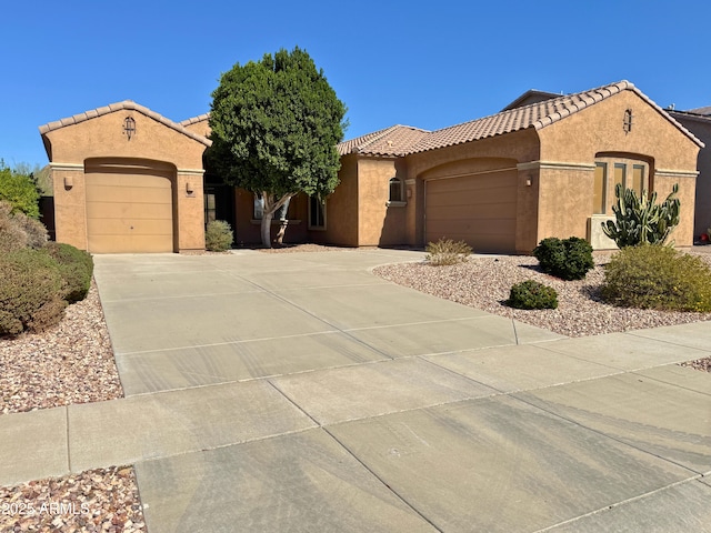 mediterranean / spanish house with a garage, driveway, and stucco siding