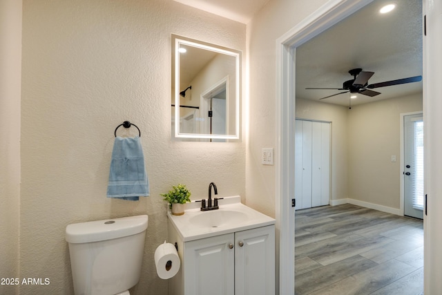 bathroom with hardwood / wood-style flooring, ceiling fan, vanity, and toilet