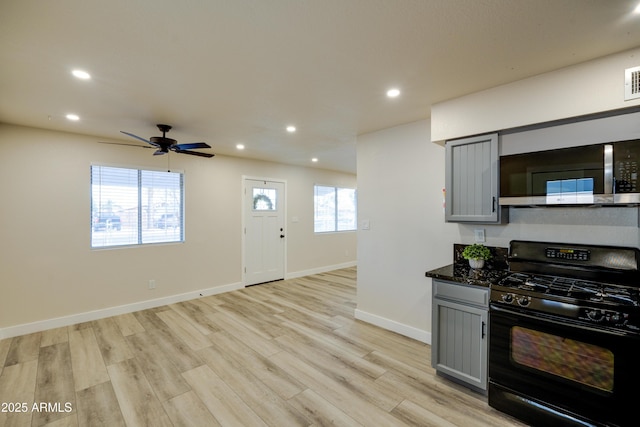 kitchen featuring black gas range oven, gray cabinets, ceiling fan, dark stone counters, and light hardwood / wood-style floors