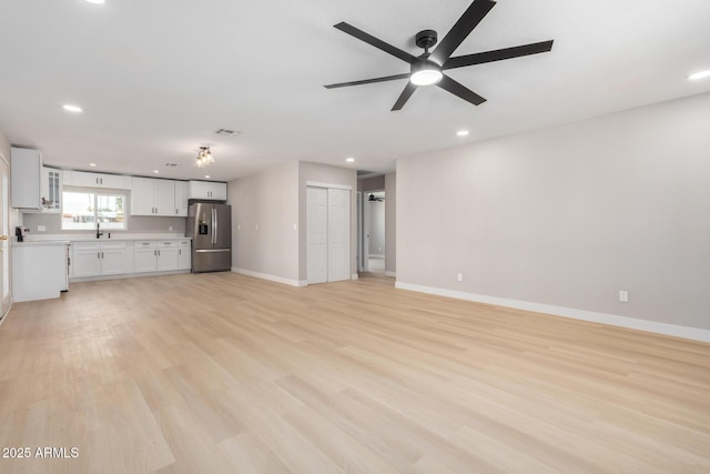 unfurnished living room with ceiling fan, light wood-type flooring, and sink