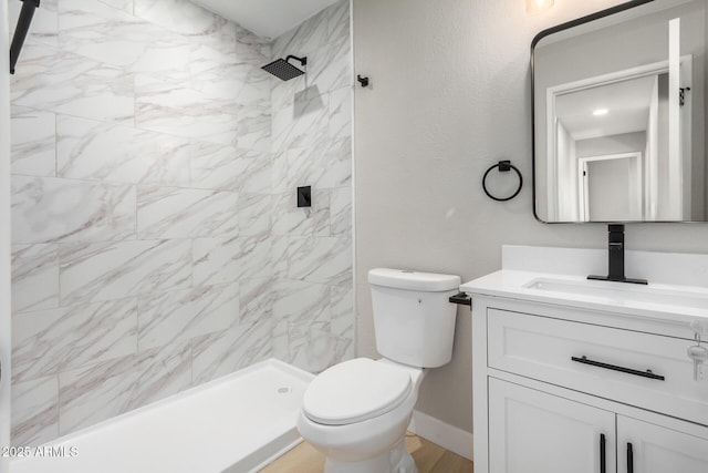 bathroom with vanity, toilet, and tiled shower