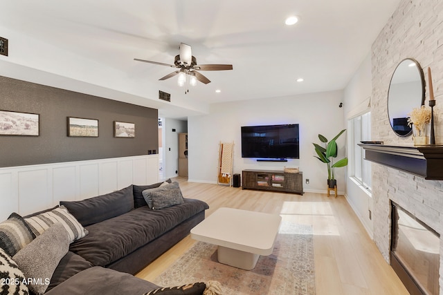 living area featuring a ceiling fan, visible vents, light wood-style flooring, recessed lighting, and a stone fireplace