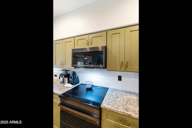 kitchen with light stone countertops, tasteful backsplash, and appliances with stainless steel finishes