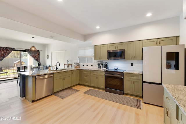 kitchen featuring light wood finished floors, backsplash, appliances with stainless steel finishes, a peninsula, and a sink