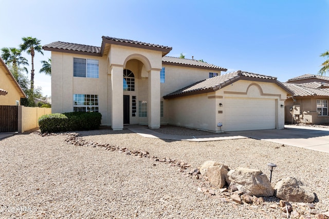 mediterranean / spanish-style house featuring fence, driveway, an attached garage, stucco siding, and a tiled roof