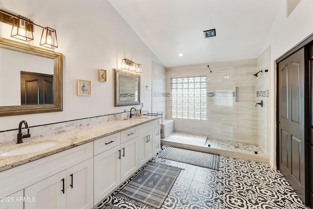 bathroom featuring vaulted ceiling, a stall shower, and a sink