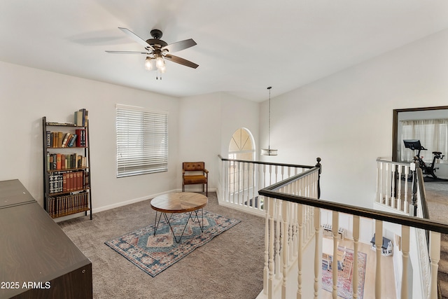 sitting room featuring baseboards, a ceiling fan, an upstairs landing, and carpet flooring