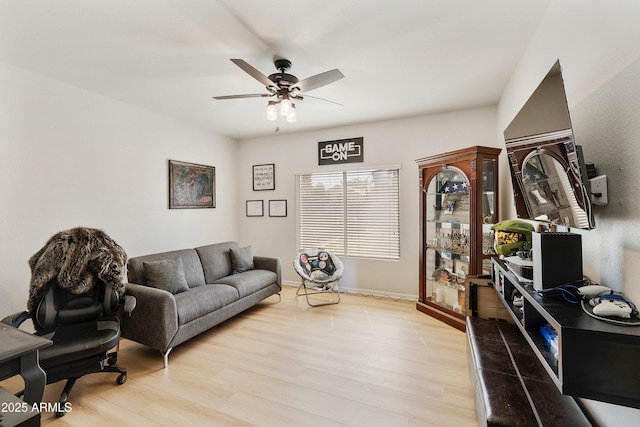 living area featuring baseboards, light wood-type flooring, and ceiling fan