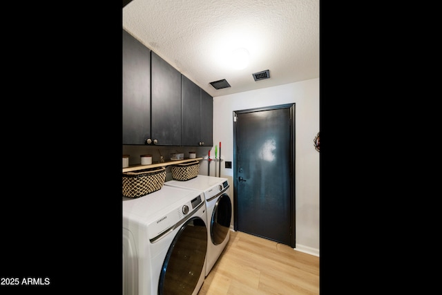 clothes washing area with visible vents, light wood finished floors, cabinet space, a textured ceiling, and washing machine and dryer