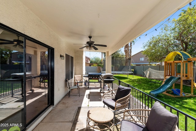 view of patio / terrace featuring a fenced backyard, ceiling fan, a playground, and a trampoline